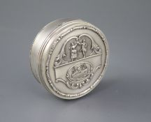 A George V silver circular box and hinged cover, embossed with a ship and dancing figures above,