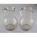 A pair of Georgian glass plain baluster jugs, first half 18th century, each with an applied scrolled