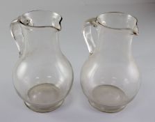 A pair of Georgian glass plain baluster jugs, first half 18th century, each with an applied scrolled