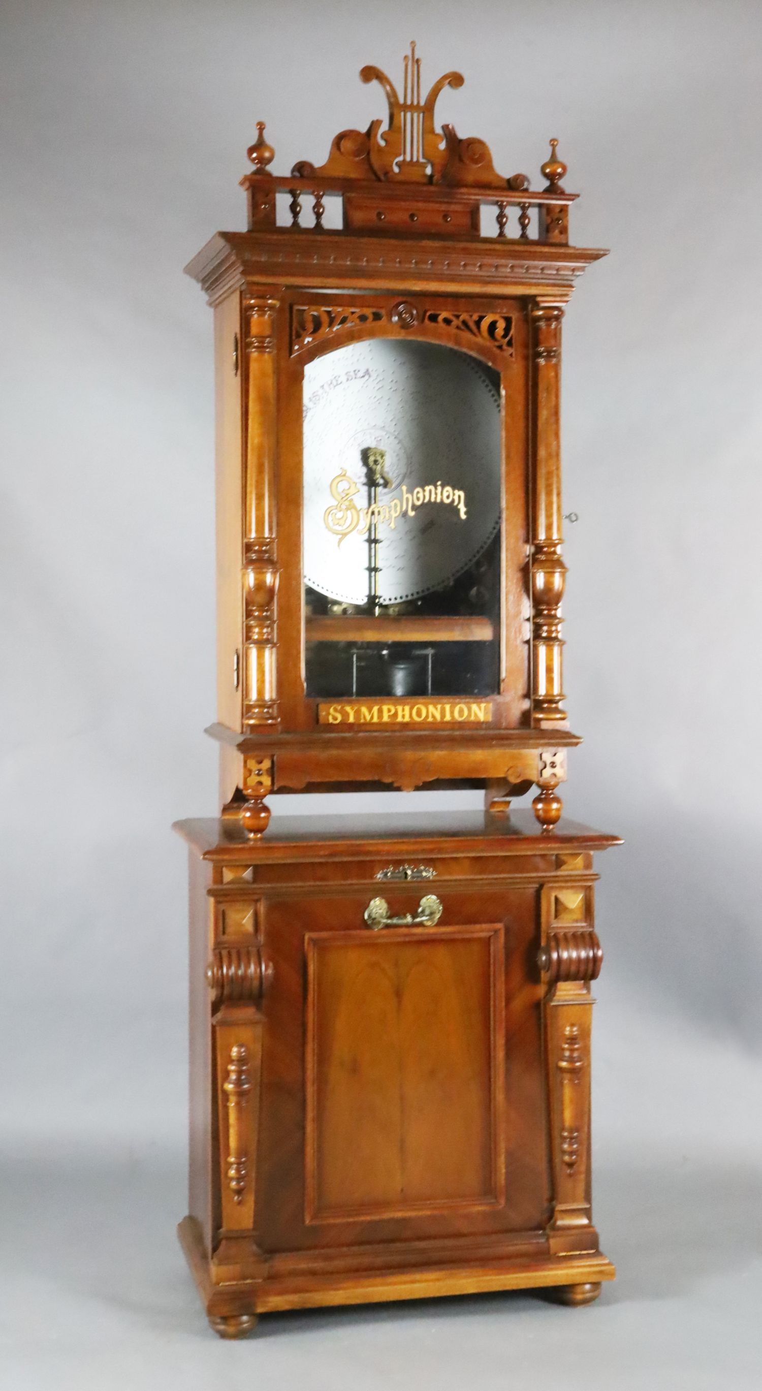 A late 19th century German walnut cased upright Symphonion, with lyre shaped pediment, pilaster
