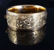 A late 1950's engraved 9ct gold hinged bangle, 39.3 grams.CONDITION: Some scratches to the the