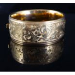 A late 1950's engraved 9ct gold hinged bangle, 39.3 grams.CONDITION: Some scratches to the the