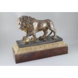 An early 19th century cast iron model of a lion standing with it's foot upon a brass ball, on marble