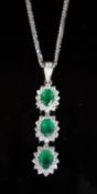 A modern 18ct white gold, emerald and diamond set oval triple cluster drop pendant, on an 18ct white