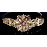 An ornate pierced 14ct gold, ruby and diamond set tapering bracelet, with central flower head motif,