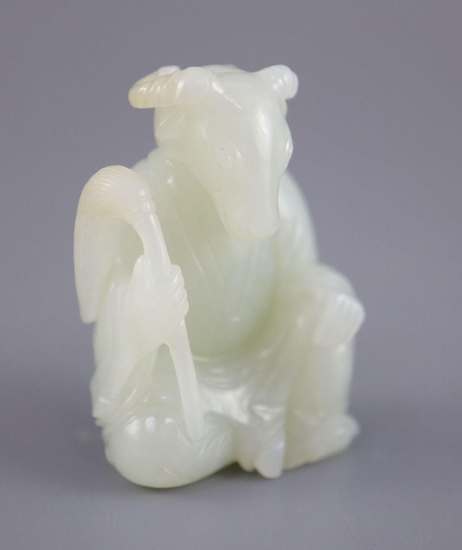 A Chinese pale celadon jade seated figure of a ram-headed immortal, seated wearing flowing robes and