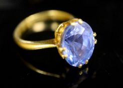 A gold (stamped 24k) and solitaire oval cut Ceylon sapphire set ring, maker's W. Bros, the stone