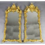 A pair of 19th century French carved giltwood wall mirrors, with scallop and scroll crests flanked