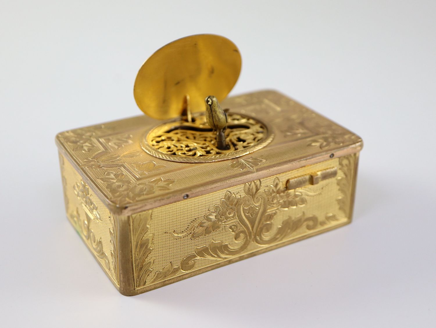 A late 19th century Swiss ormolu singing bird box, with flower and scroll engraved case, catch