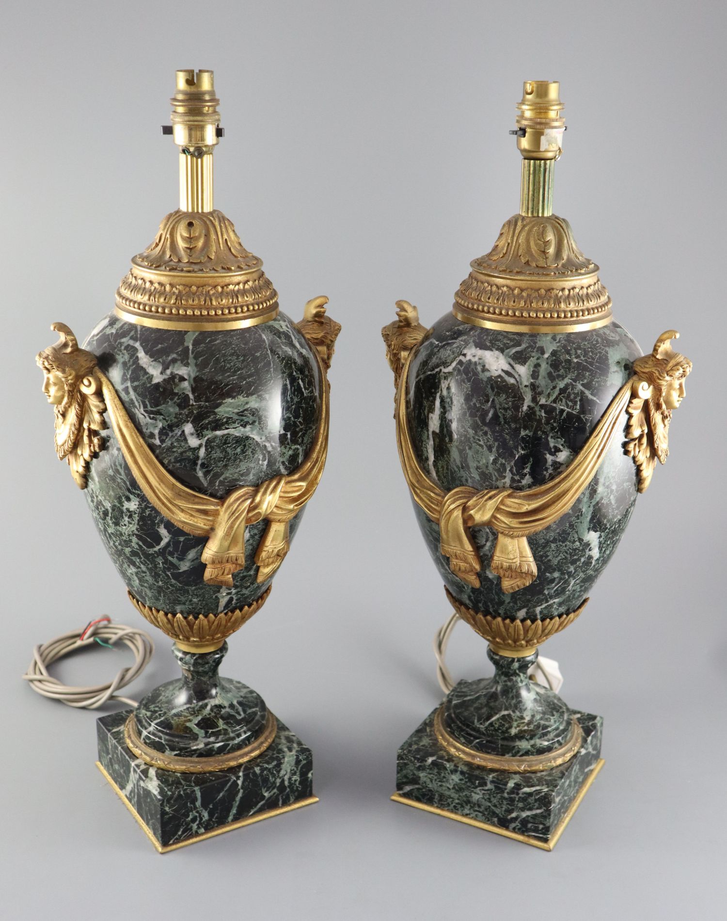 A pair of early 20th century ormolu green marble table lamps, with ovular form with mask lug handles