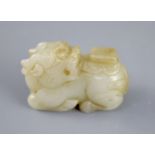 A Chinese pale celadon jade figure of a recumbent qilin, the stone with some russet inclusions, 5.