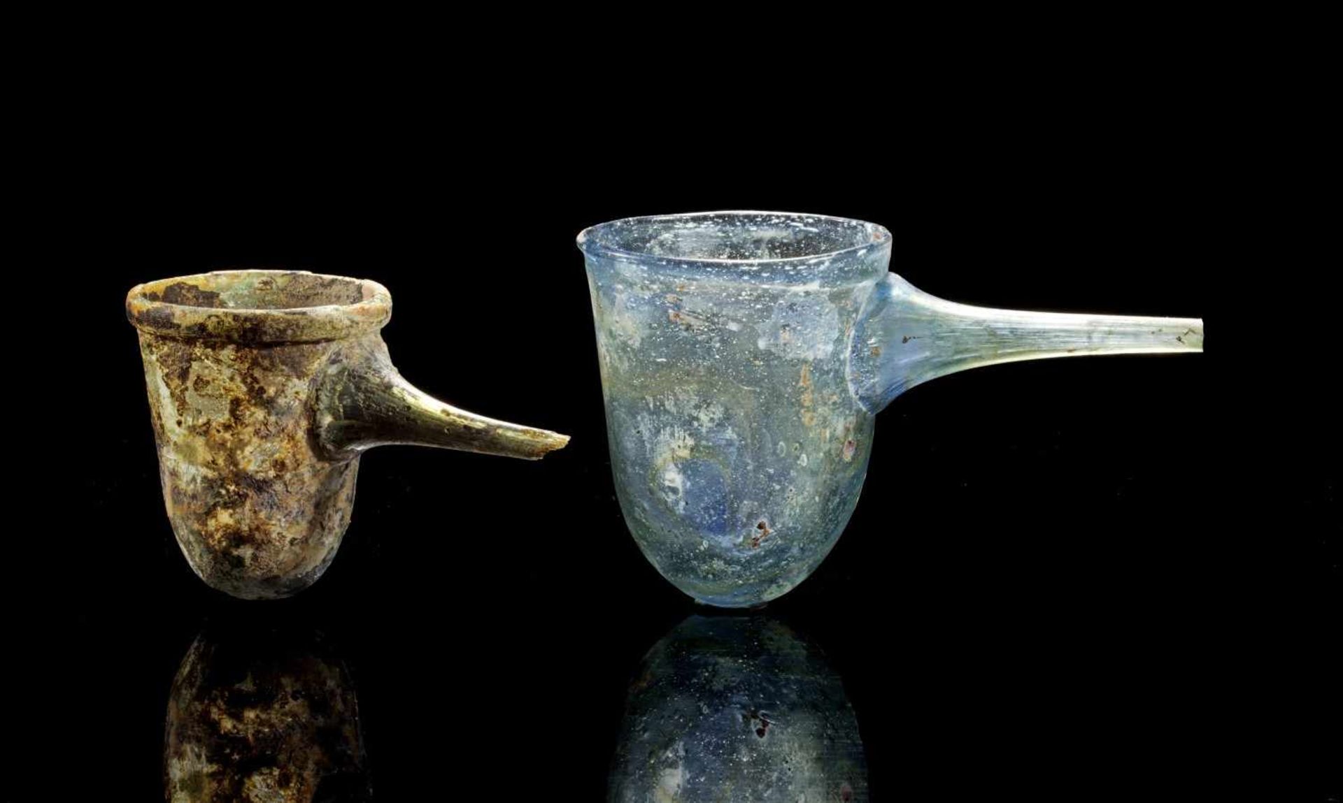 Zwei Alembiks. Islamisch, 6. - 12. Jh. n. Chr. H 7,8cm und 6,2cm. Aus blauem Klarglas.