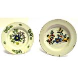 TWO 18TH CENTURY ENGLISH DELFT PLATES with painted floral decoration, 24cm diameter