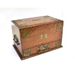 AN EDWARDIAN BRASS BOUND OAK STATIONERY CABINET with patent mechanism, the drawer action causing the