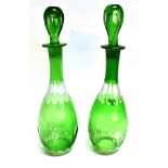 A PAIR OF GREEN FLASH CUT DECANTERS AND STOPPERS 38cm high