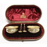 A CASED PAIR OF VICTORIAN SILVER SALTS AND SPOONS of shallow cauldron form with spiral lobes and