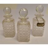 THREE MATCHING HOBNAIL CUT DECANTERS AND STOPPERS 22cm high, together with a silver 'Whisky' label