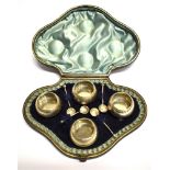 A VICTORIAN CASED SET OF FOUR SILVER SALTS AND SPOONS of circular cauldron form, on three ball feet,