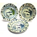 THREE 18TH CENTURY DELFT CHARGERS each similarly decorated with birds beside a tree and pond, each
