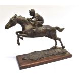 A RESIN GROUP OF A RACEHORSE AND JOCKEY in flight on a rectangular wooden base, height 33cm, width