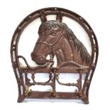 A CAST BRIDLE RACK in the form of a horses head, with a horseshoe and fitted with three swinging