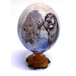 AN OSTRICH EGG painted by Sherry Rowe, with images of African game, mounted on a wooden stand