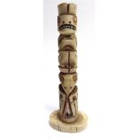 A HAIDA CARVED MARINE IVORY TOTEM POLE with stained red and black incised detail, 13.5cm high.