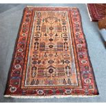 A RED GROUND RUG with stylised tree of life design, 106cm x 185cm