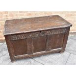 AN OAK COFFER OF PANELLED CONSTRUCTION with carved decoration to the front, on stile feet, 120cm
