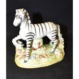 A STAFFORDSHIRE FIGURE OF A ZEBRA on naturalistic oval base, 12cm high