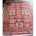 A RED GROUND RUG the central field with guls and stylised animals, 170cm x 240cm