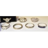 A GROUP OF SEVEN STONE SET SILVER RINGS the assorted designs set with white stones and one with a