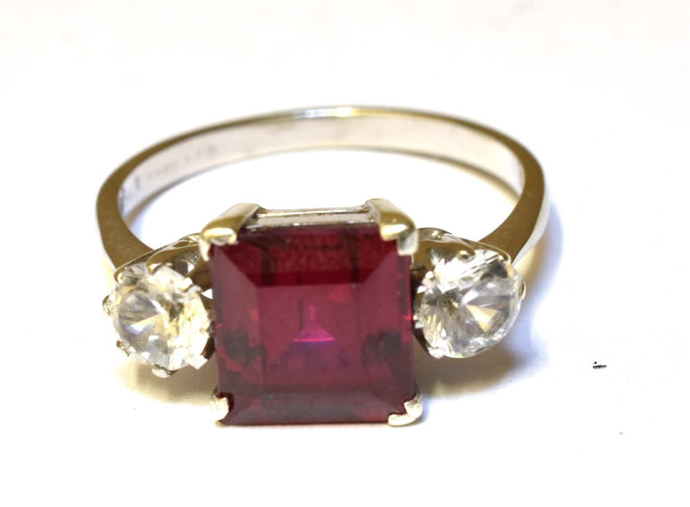 A SYNTHETIC RUBY AND SYNTHETIC WHITE SPINEL THREE STONE RING Claw settings to a 9ct white gold