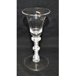 AN 18TH CENTURY WINE GLASS with trumpet shaped bowl, on triple knopped opaque twist stem and conical