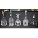 A GROUP OF FIVE GLASS DECANTERS AND STOPPERS comprising two silver mounted examples for Birmingham