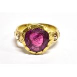 A RUBY SINGLE STONE RING with diamond set shoulders, the rub over set mixed cut ruby approx. 11mm