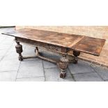 AN OAK DRAW-LEAF REFECTORY DINING TABLE the five plank top with cleated ends, frieze carved with
