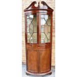 AN EDWARDIAN MAHOGANY BOWFRONT CORNER CABINET the frieze with broken swan neck pediment and urn