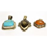 THREE SILVER STONE SET LARGE PENDANTS comprising a pear shaped smoky quartz, an oval clarified amber