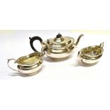 A SILVER THREE PIECE TEA SET of plain oval, squat form with beaded border, teapot with hardwood