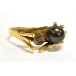 AN 18CT GOLD 1960'S DESIGN BLACK PEARL SET RING The two bead ring with one bead missing,
