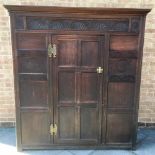 A PANELLED OAK HALL CUPBOARD with moulded frieze, lunette carved decoration to front, with pair of
