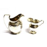 TWO SILVER MILK JUGS comprising a Georgian helmet shape with long strap handle (hallmarks rubbed),