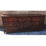 A GEORGE III OAK DRESSER BASE fitted with three drawers above central cupboard with pair of