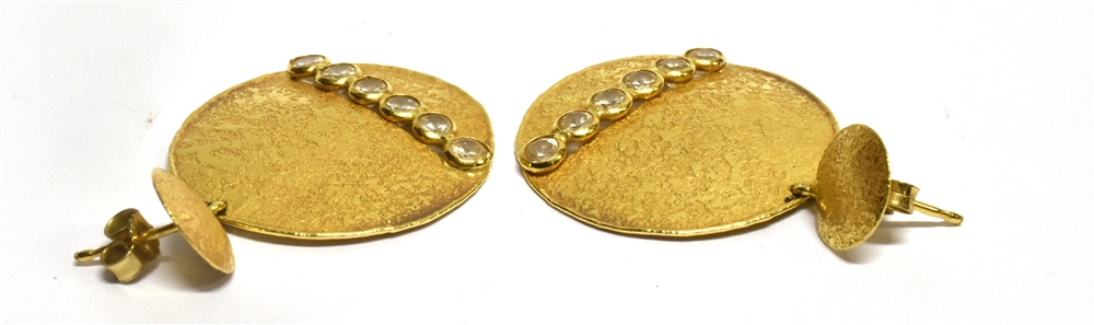 A PAIR OF DIAMOND SET DROP EARRINGS the round disc drops of textured finish, each with a row of