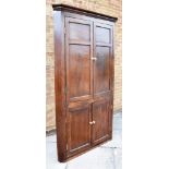 A LARGE PANELLED OAK CORNER CABINET with moulded frieze, shaped shelves to interior, 114cm wide