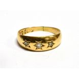 AN 18 CARAT GOLD DIAMOND THREE STONE GYPSY SET YELLOW GOLD BAND RING three small diamonds, ring size