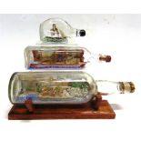 THREE MODEL SHIPS IN BOTTLES the largest 29.5cm long and on an oak display stand.