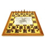 A GOLD-PLATED CAST METAL CHESS SET the kings 6.5cm high; together with a chess board, 36.25cm x 36.