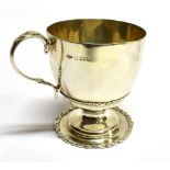 A SILVER CHRISTENING MUG of baluster form on pedestal base, c-scroll handle, applied border,